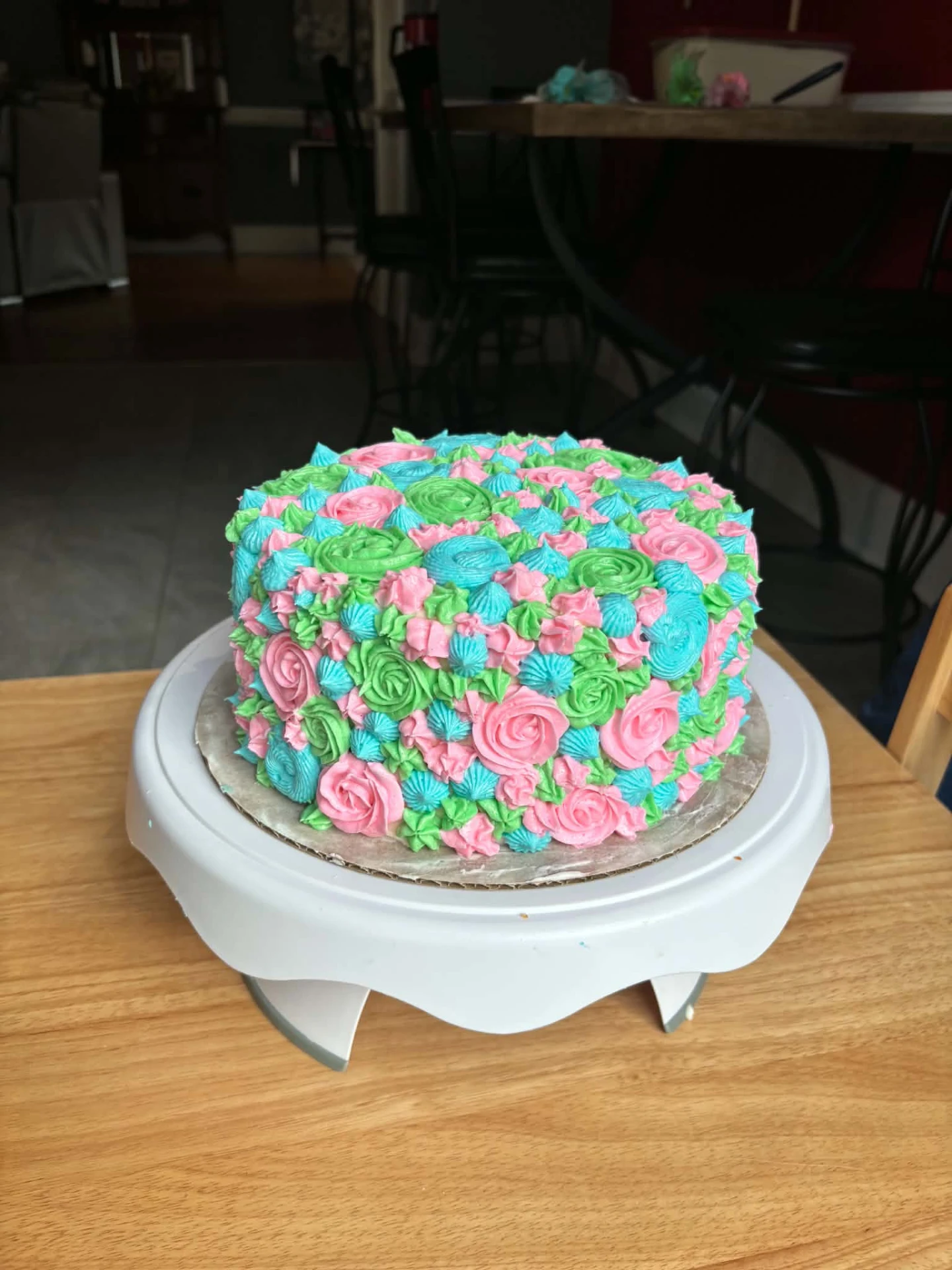 Layer cake covered in pink, green and blue buttercream rosettes